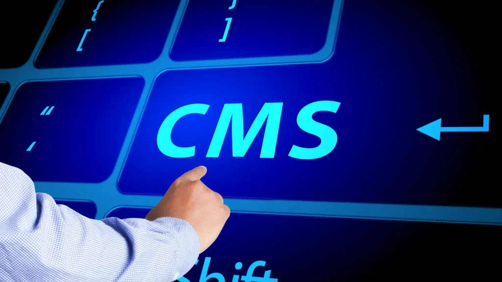 Finger pointing at a computer keyboard with 'CMS' highlighted for web development.