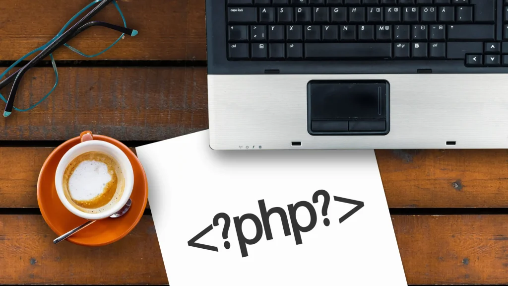 PHP code on a document next to a laptop, representing the power of PHP in modern website development.