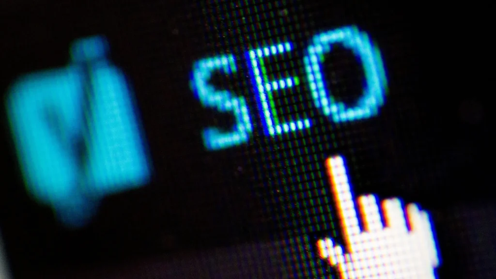 A close-up image showing the SEO button with a hand cursor pointing to it on a digital screen.